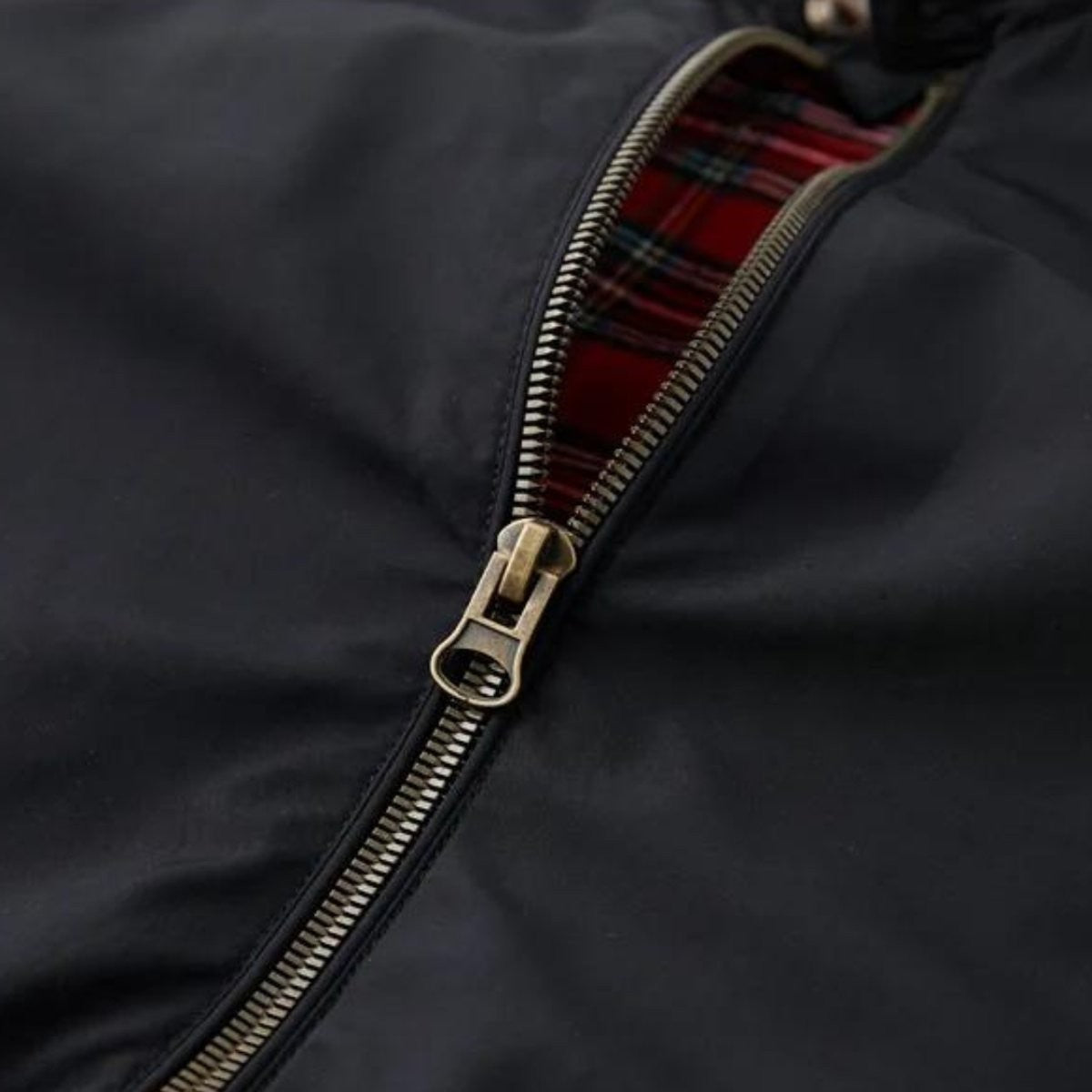 Close-up of bronze zip pull against red tartan jacket lining