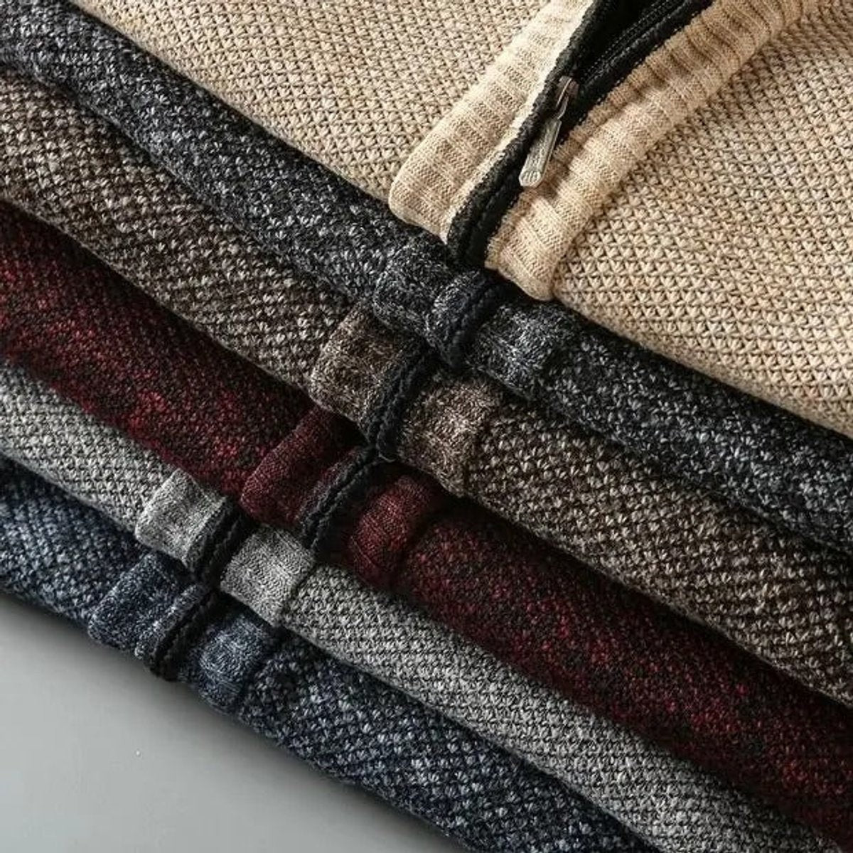 Stack of textured knit zip-up jackets in assorted colourways