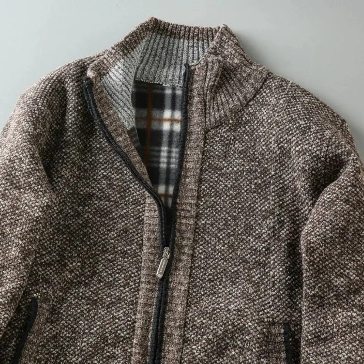 Close-up of ribbed collar and tartan lining on knit bomber jacket