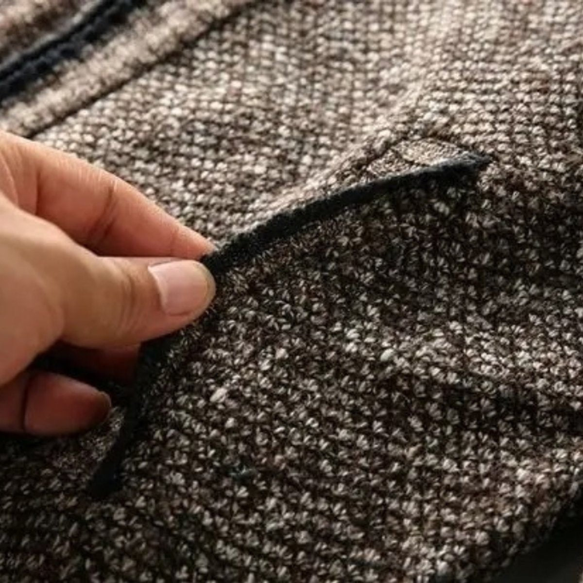 Fingers touching frayed knit edge showing jacket pocket detail