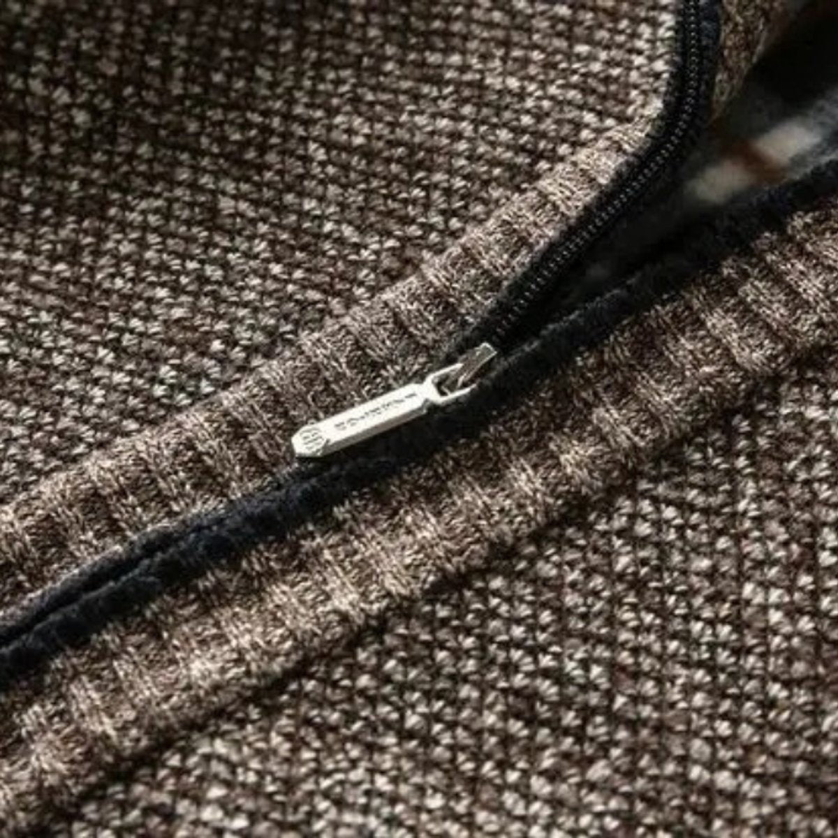 Zip pull close-up on textured brown knit bomber jacket