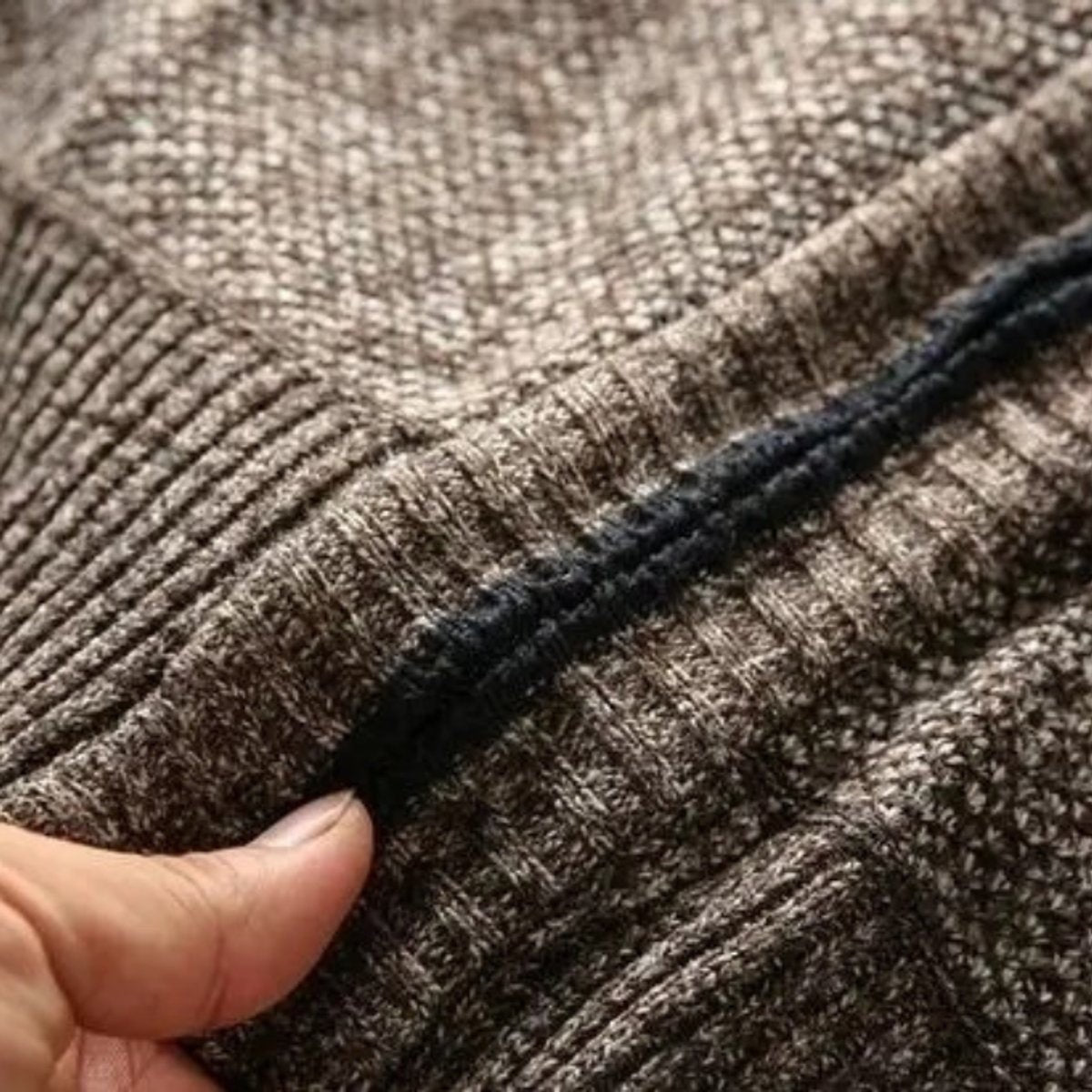 Hand pinching ribbed knit trim along jacket zip seam
