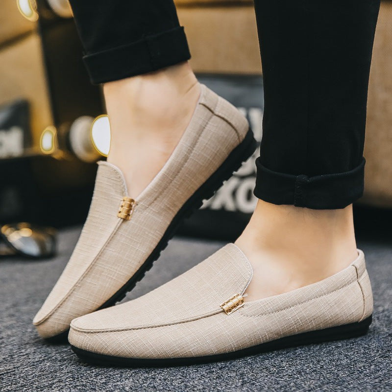 Beige canvas slip-on loafers worn with rolled black trousers