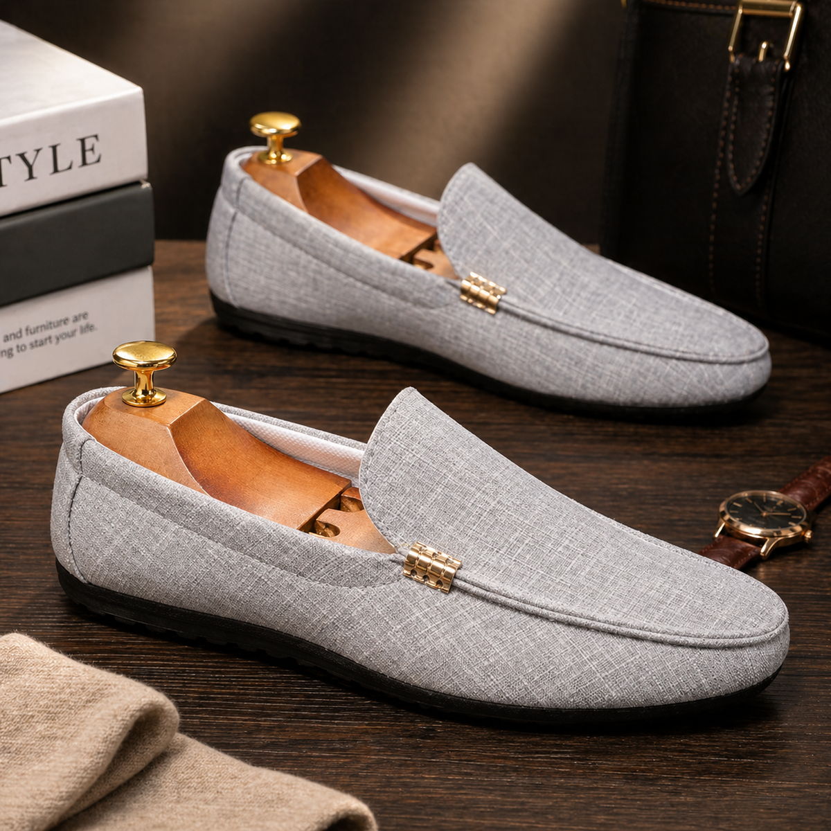 Grey woven canvas loafers with gold buckle, arranged beside accessories