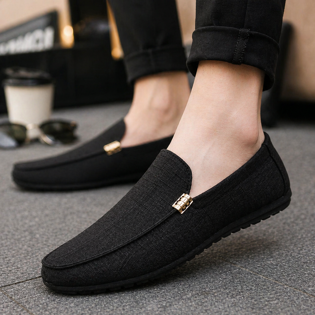 Black canvas slip-on loafer worn on foot with rolled trousers