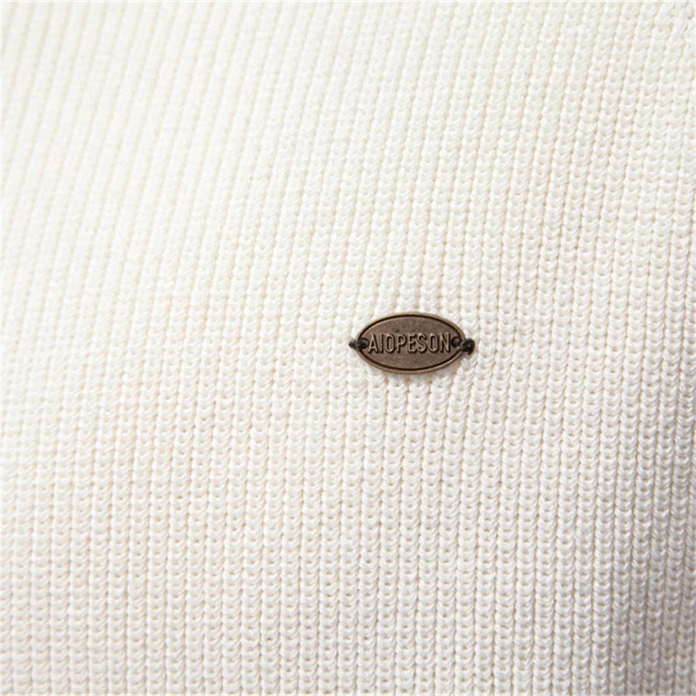 Close-up of cream ribbed knit fabric with branded metal logo tag