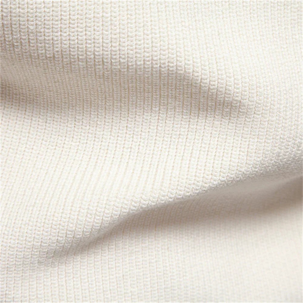Close-up texture of cream ribbed knitwear fabric on jumper