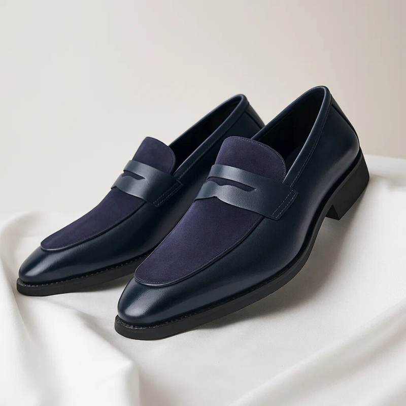 Pair of navy suede penny loafers with leather strap detail on white fabric