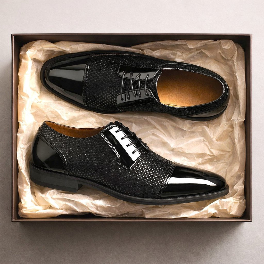 Pair of black patent cap-toe Oxford shoes displayed inside a gift box