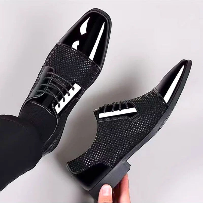 Hand holding black patent cap-toe Oxford shoe showing textured side panel