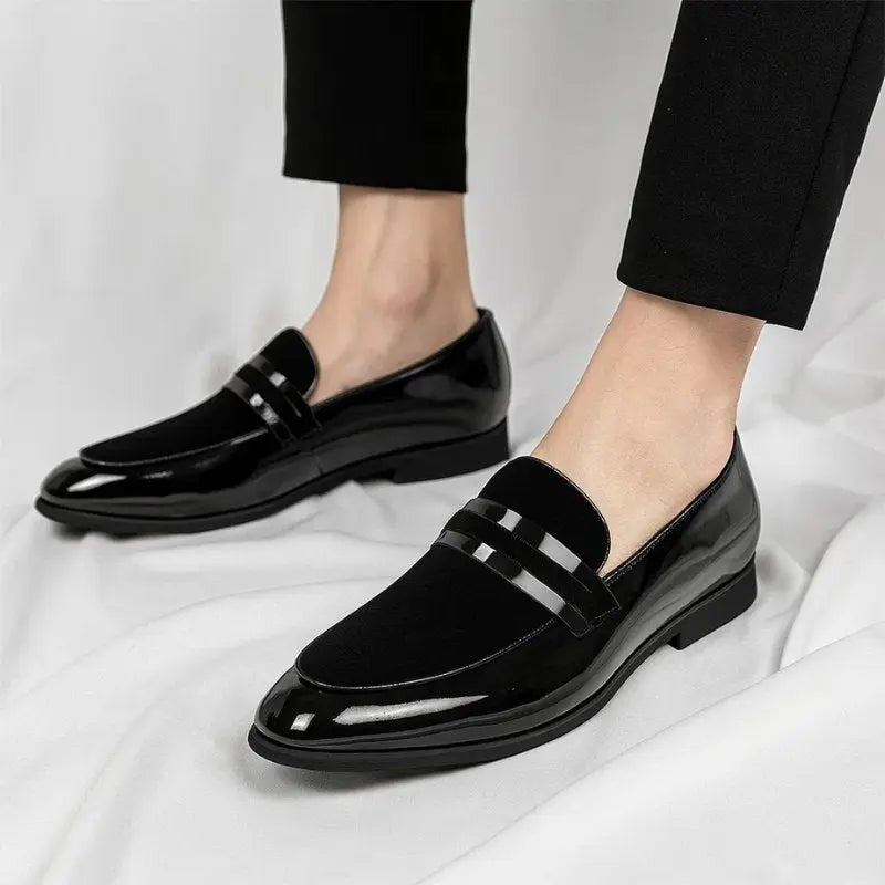 Black patent loafers styled on feet with slim-fit black trousers