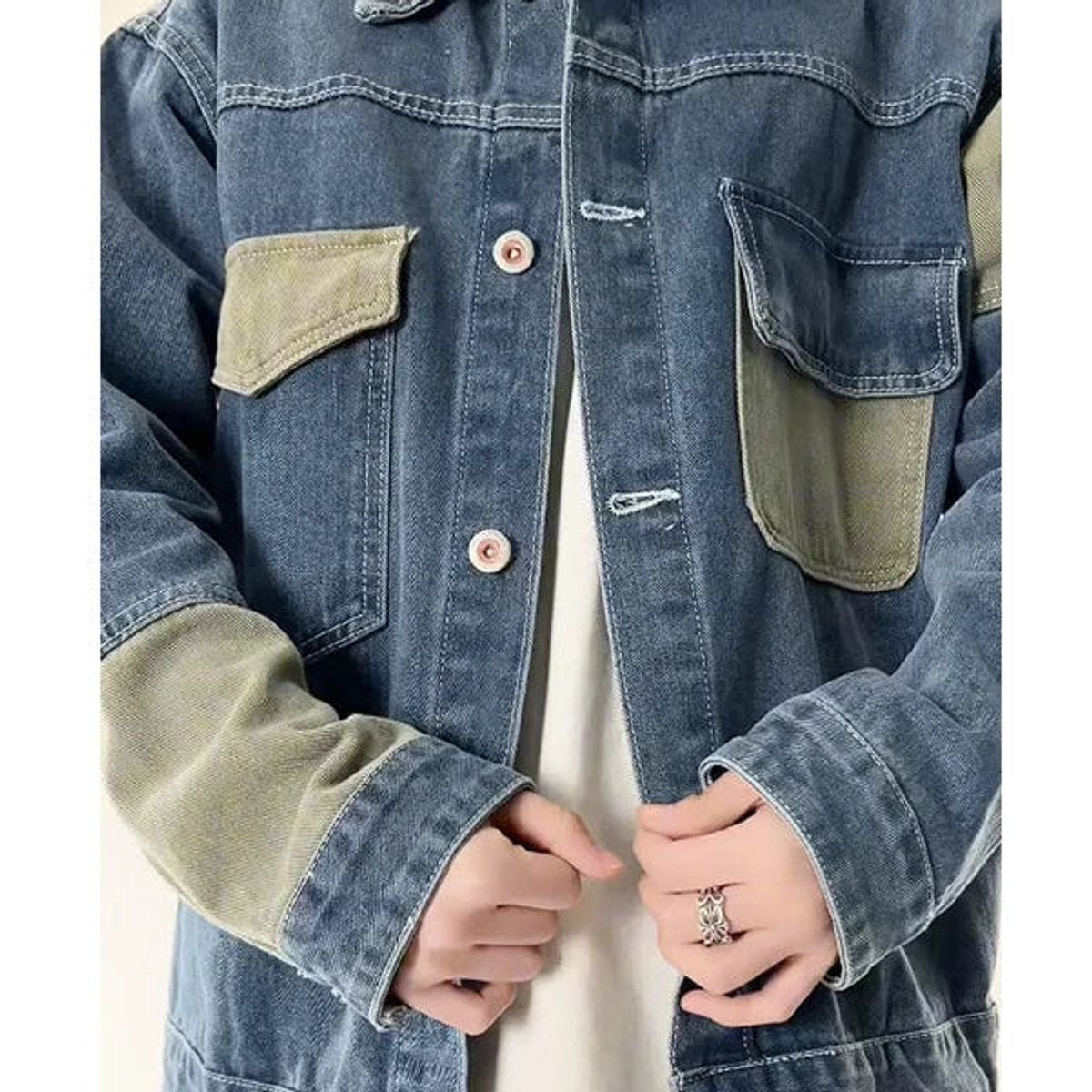 Close-up of two-tone denim jacket cuffs and buttoned utility pockets