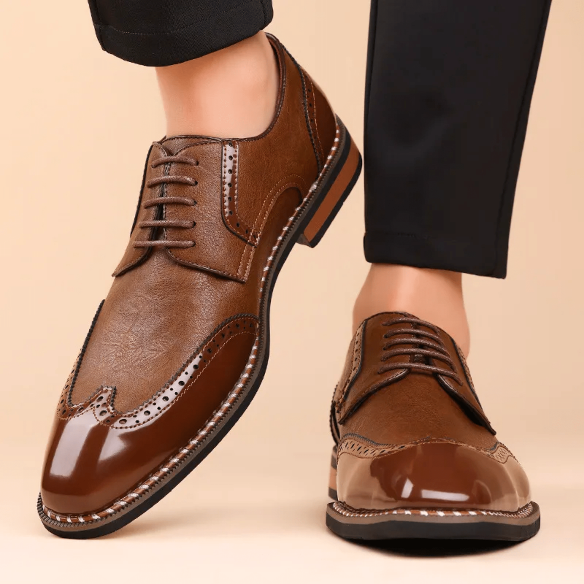 Close-up of tan wingtip brogue Oxford shoes worn with black trousers