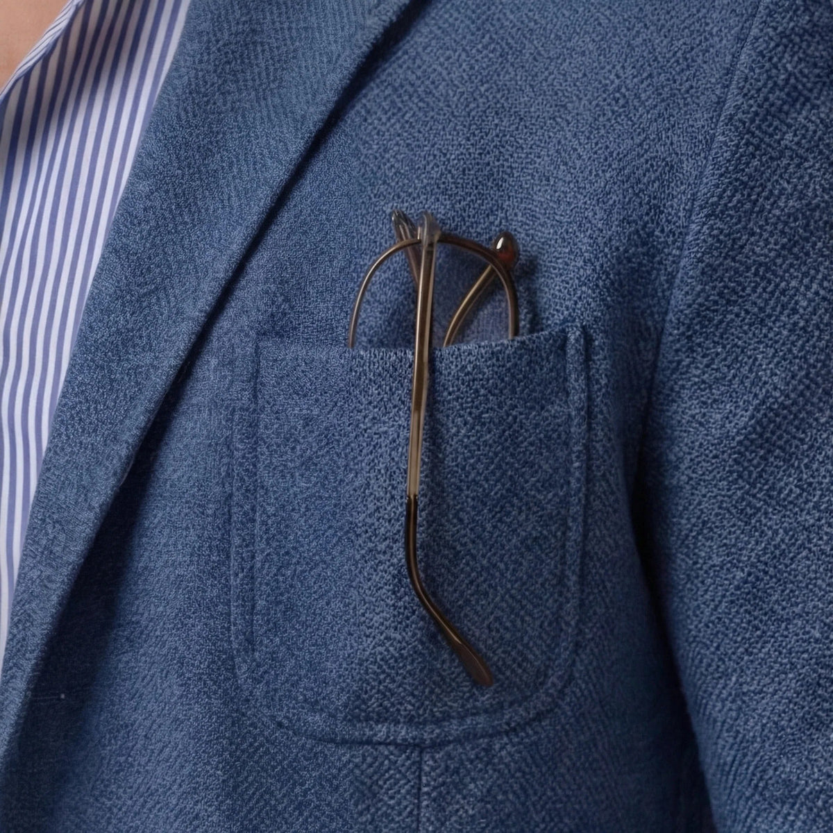 Side profile of blue blazer with glasses tucked into chest pocket