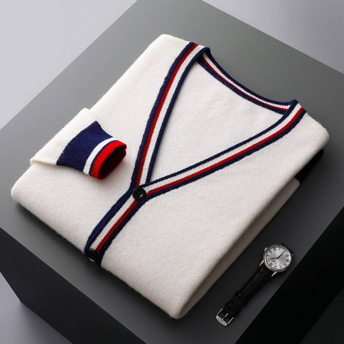 Folded white knitted cardigan featuring navy and red striped V-neck trim