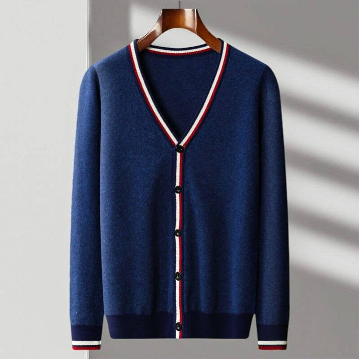 Navy V-neck cardigan with striped trim and button placket hanging on wooden hanger