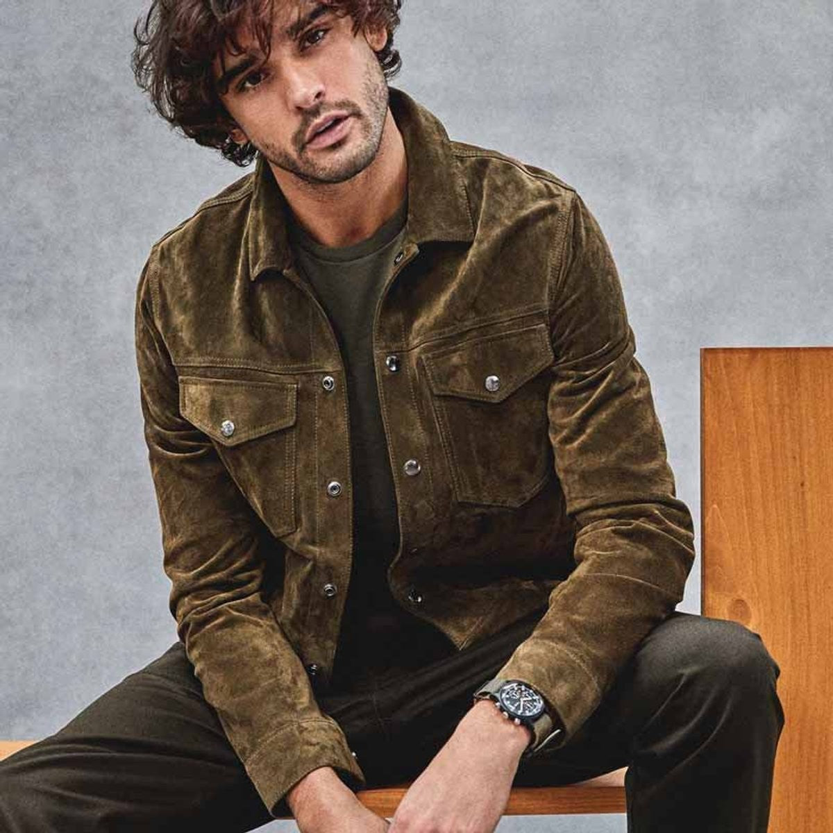 Man seated wearing vintage suede bomber jacket with buttoned cuffs
