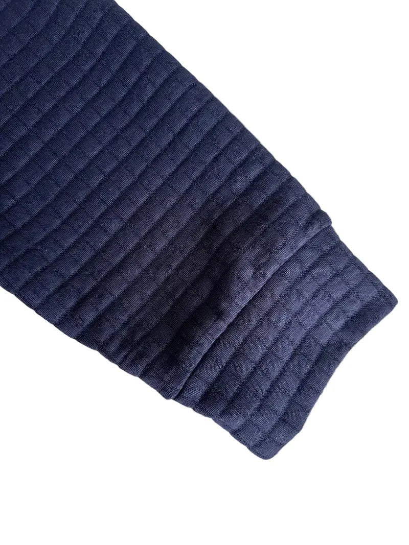 Detail shot of navy polo's ribbed cuff and waffle fabric