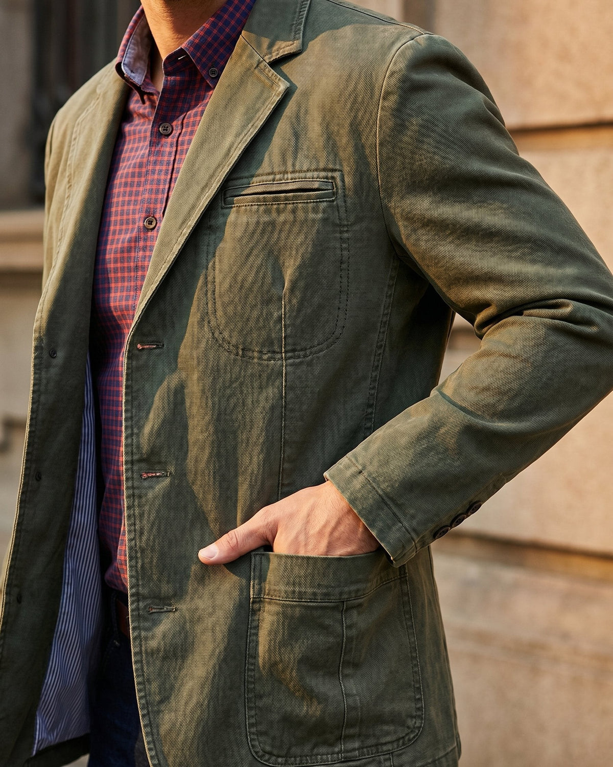 Man wearing olive washed denim blazer with hand in pocket, close-up detail