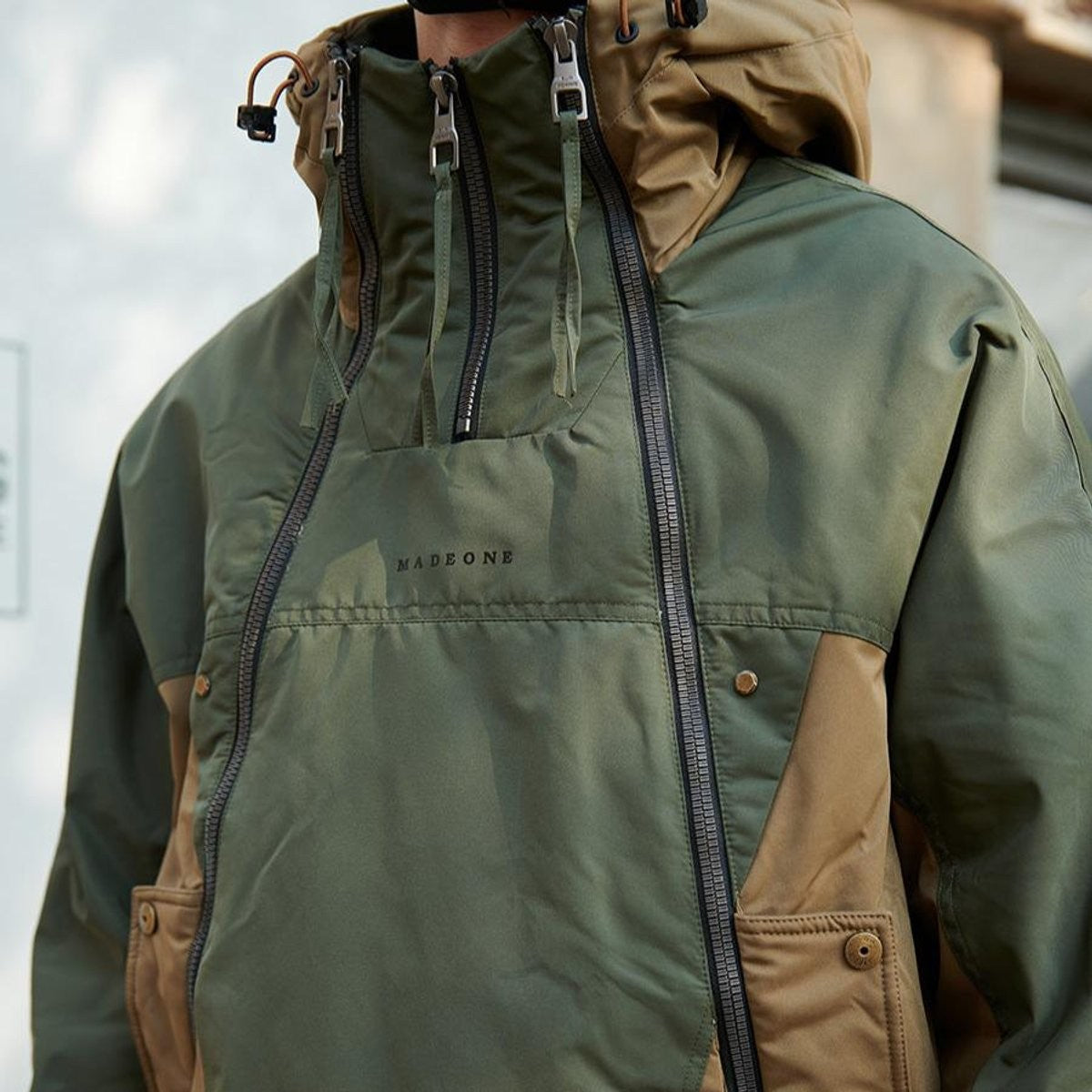 Man wearing khaki colour-block waterproof jacket with triple-zip funnel neck