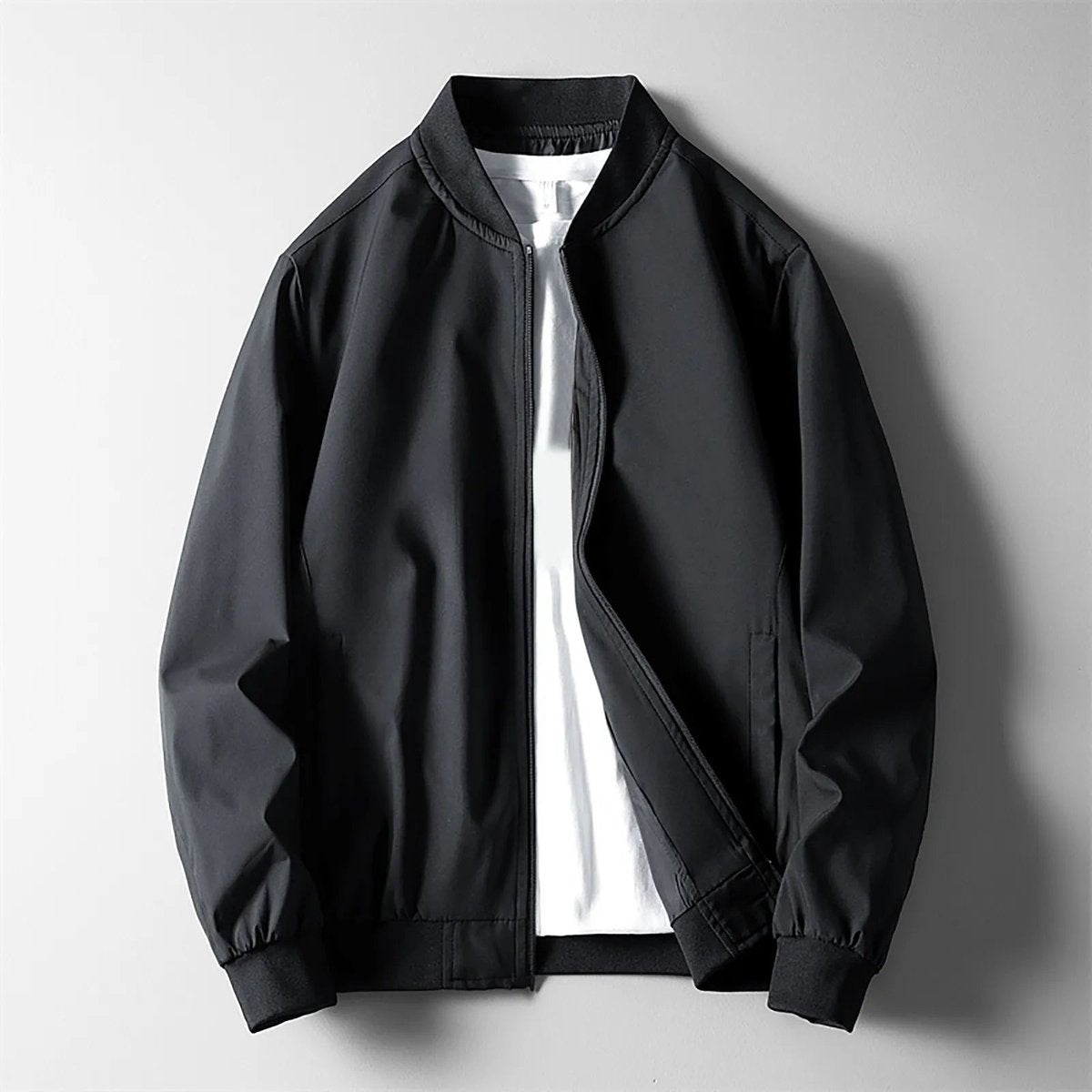 Black wind-resistant bomber jacket featuring ribbed cuffs and stand collar