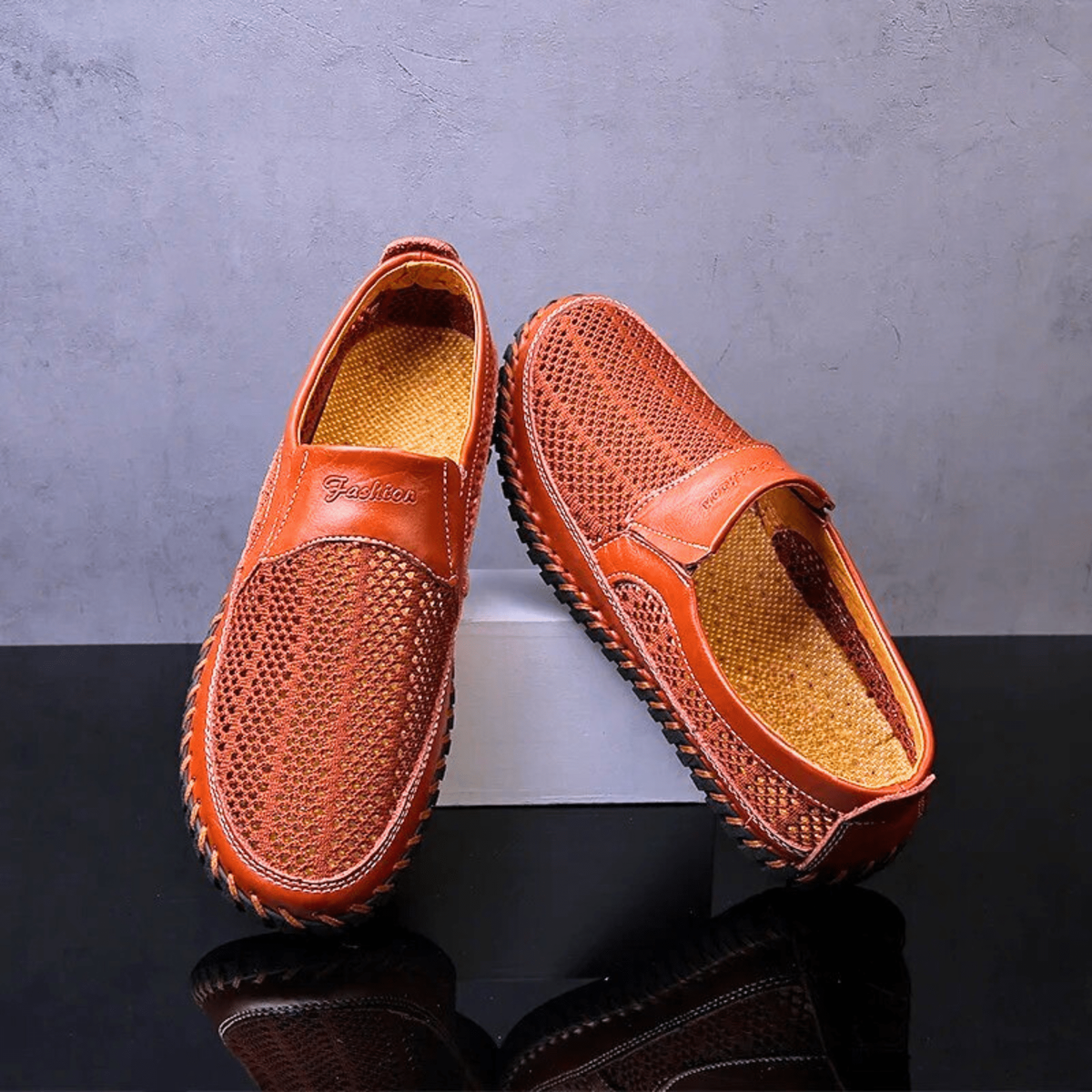 Pair of orange leather slip-on shoes showing tan insoles and woven texture