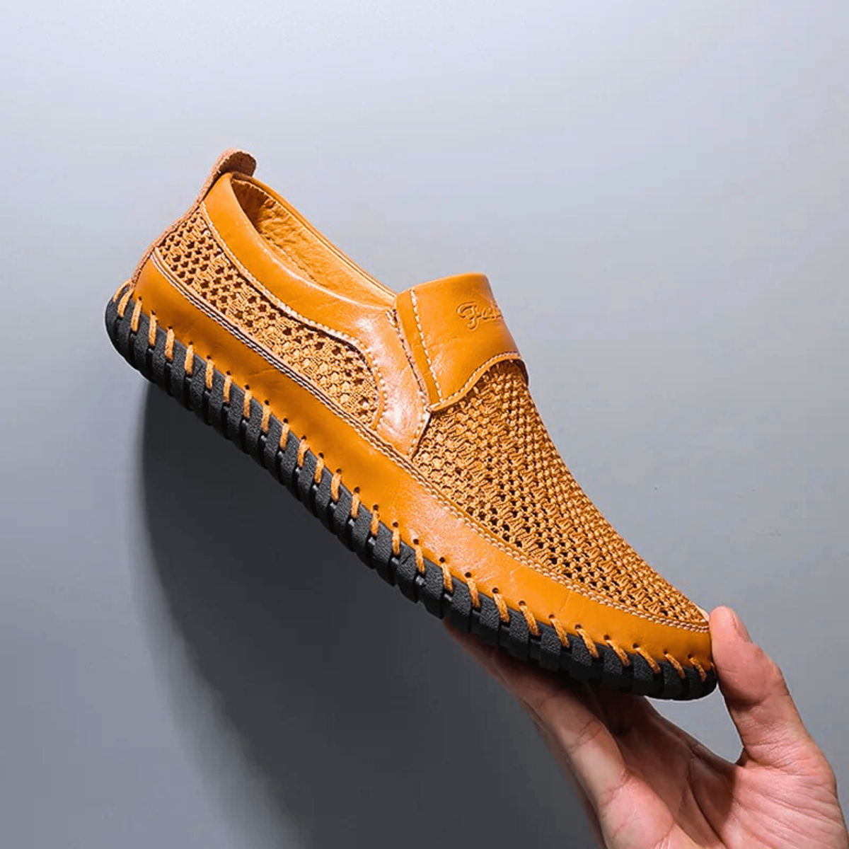 Mustard yellow leather loafer with mesh side panels and hand-stitched trim