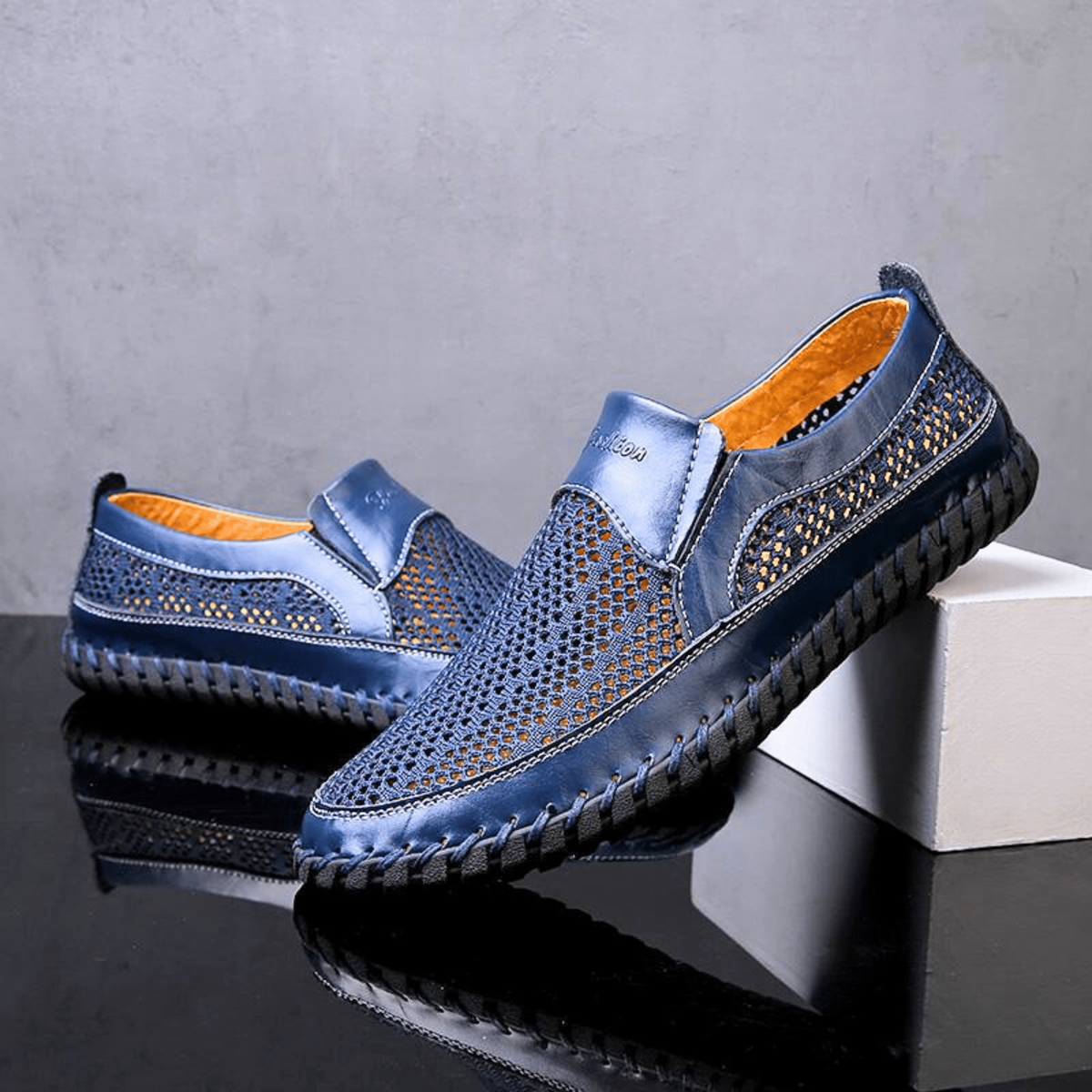 Pair of navy leather slip-on shoes with mesh panels and stitched soles